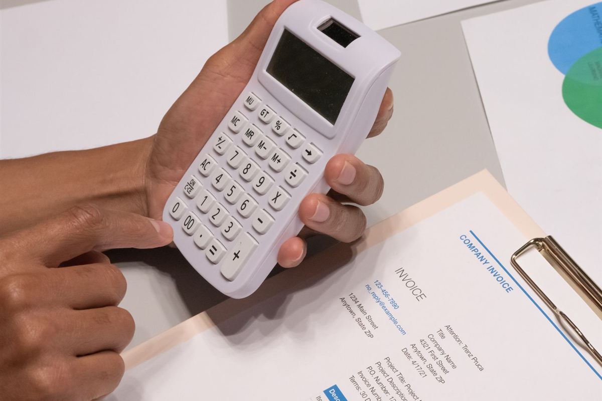 Person using a calculator while reviewing an invoice