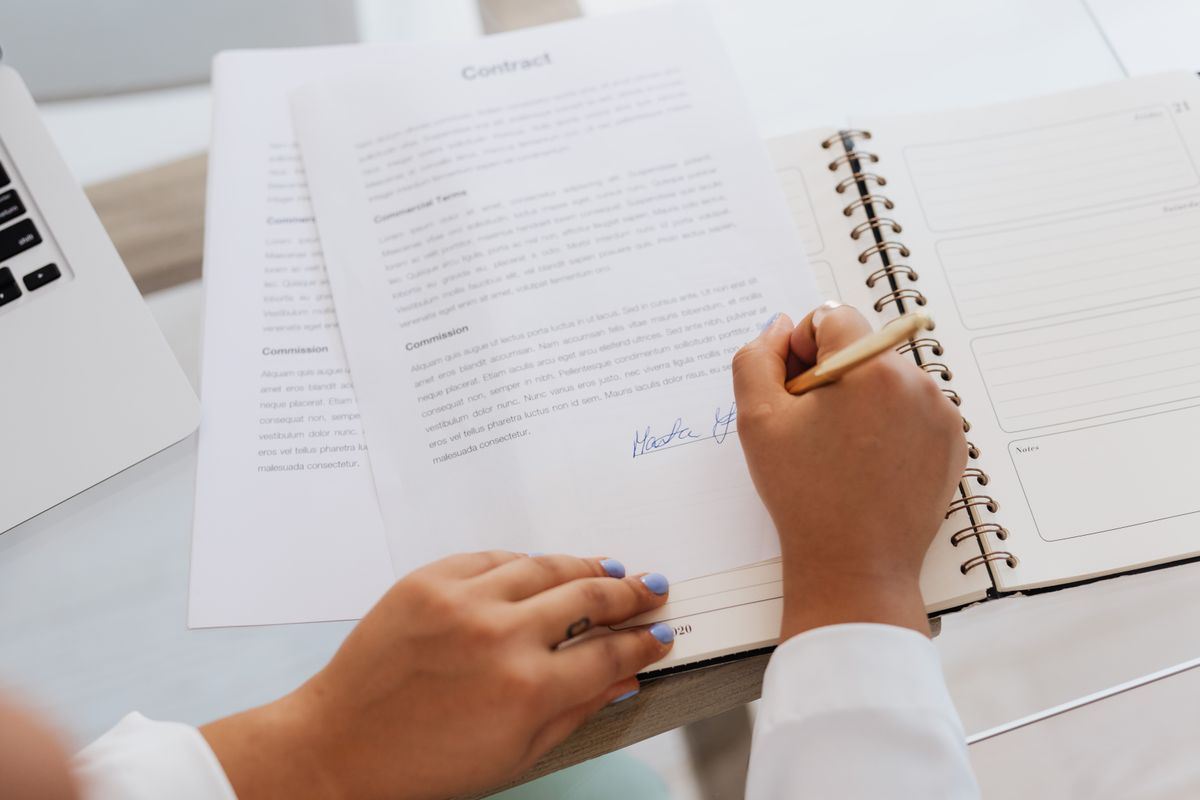 Person signing a service contract at a desk