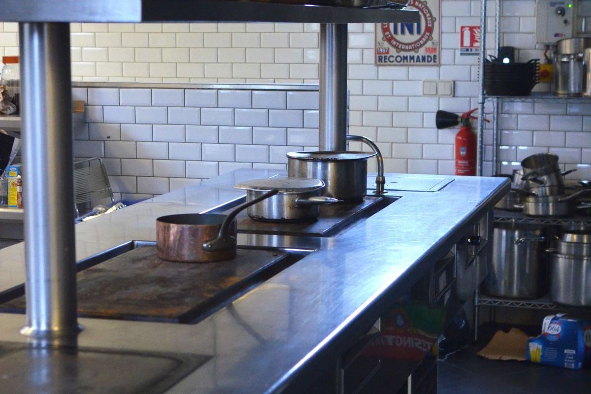 Clean commercial restaurant kitchen with stainless steel work surfaces