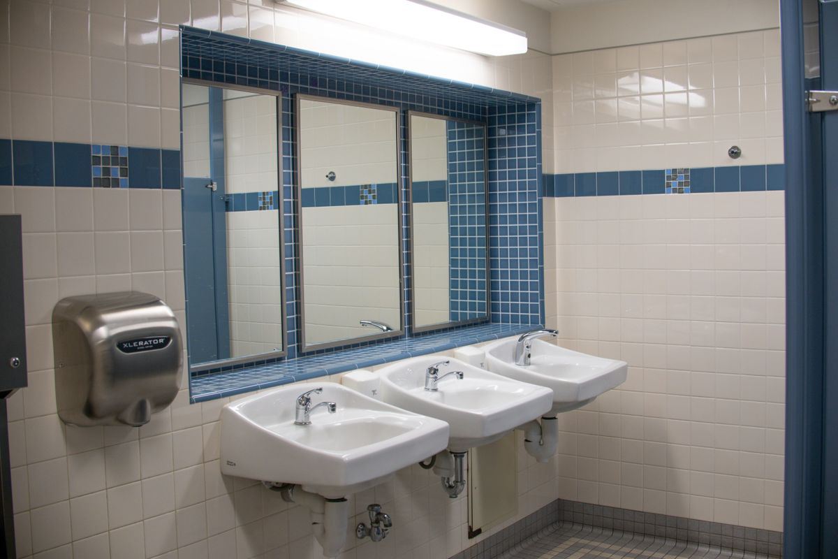Clean commercial restroom with a row of sinks, mirrors, and a hand dryer