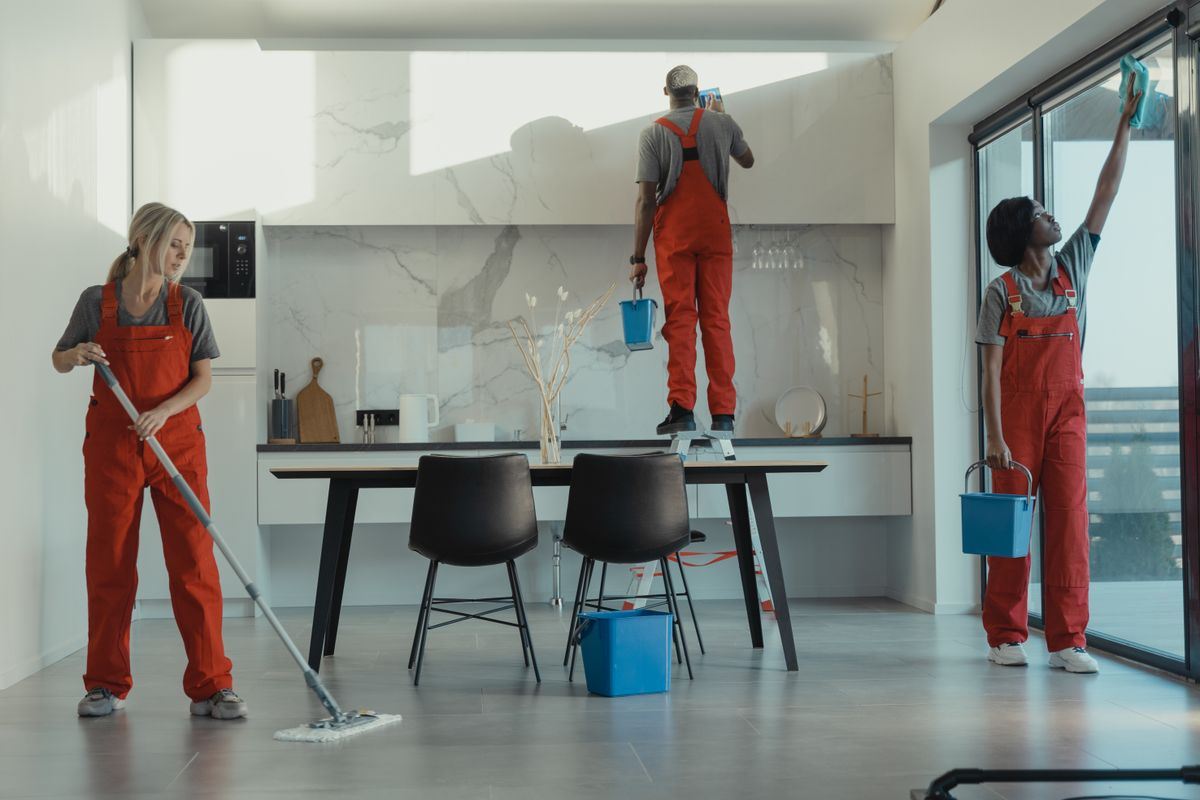 Cleaning crew mopping floors and washing glass during a deep clean
