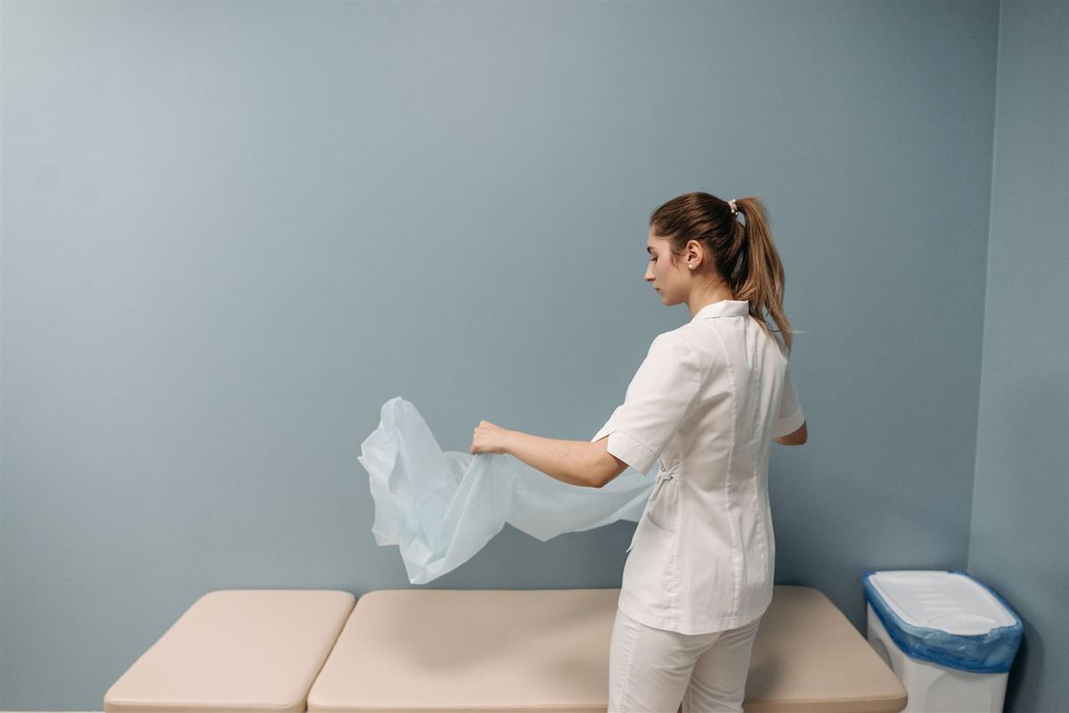 Staff member placing a protective cover on a medical exam table