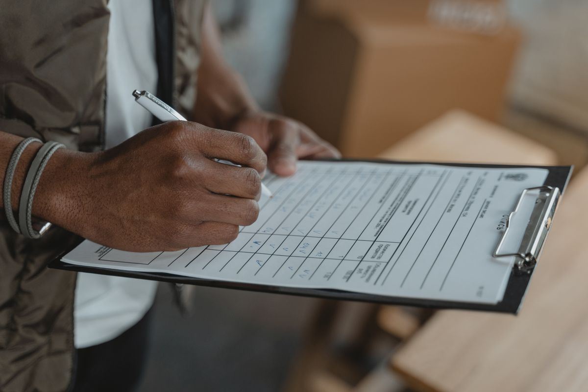 Person filling out a checklist on a clipboard