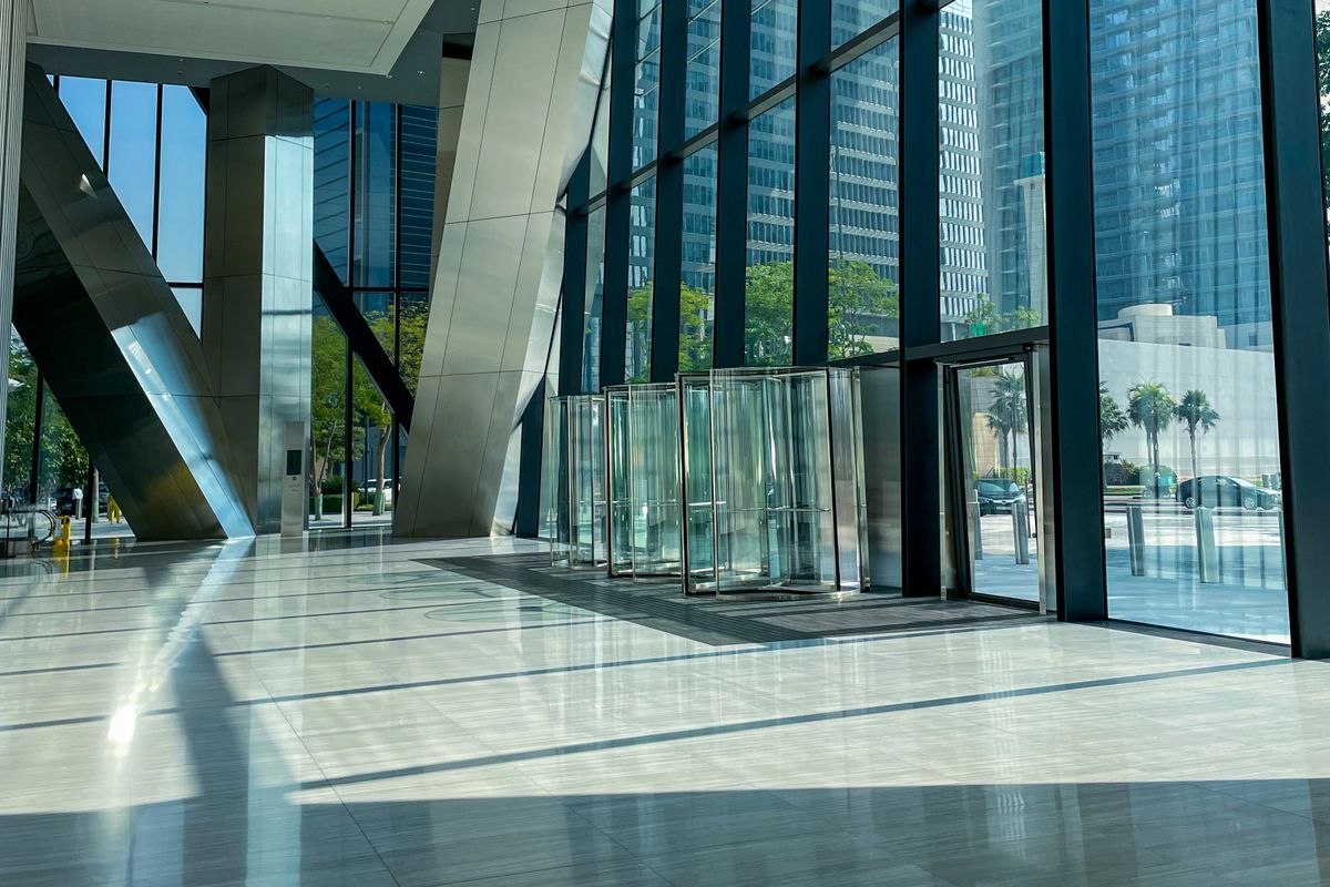 Bright high-rise office lobby with revolving doors, entrance mats and polished stone floors